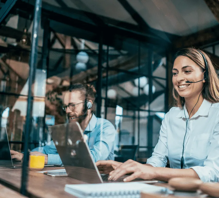 Two support engineers working at computers with headsets